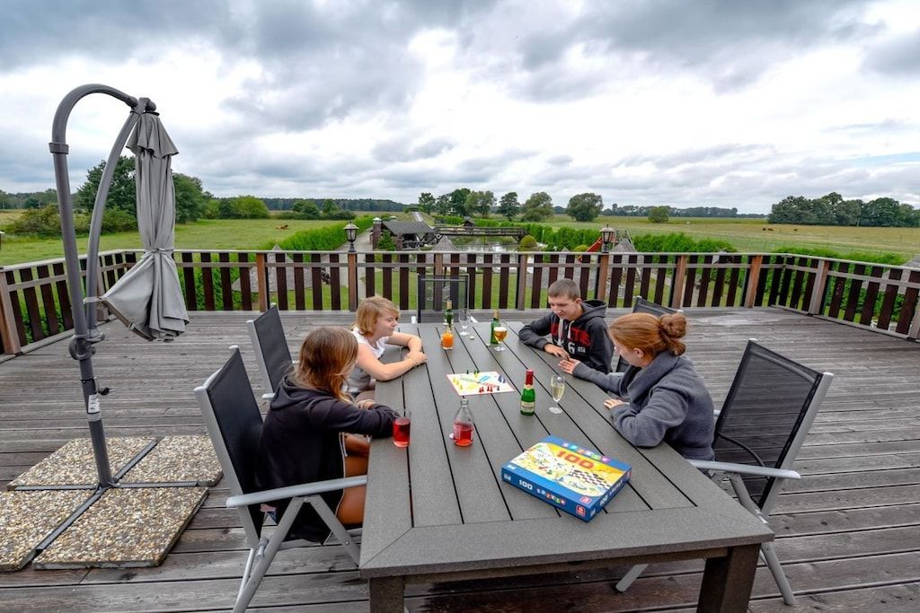 A group of people seated at a table on an outdoor deck with a view of a green landscape.