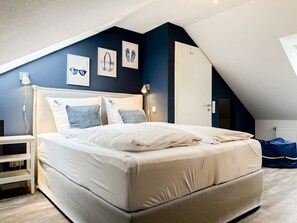 Ein Schlafzimmer mit einem Bett, einem Nachttisch und einer Wand mit gerahmten Bildern.