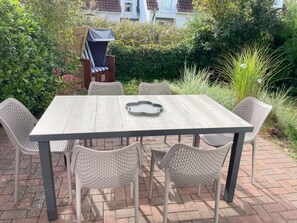 Eine Außenpatio mit einem rechteckigen Tisch und sechs Stühlen.