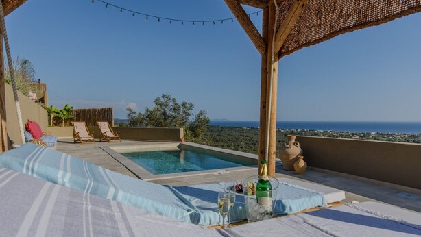 A rooftop terrace with a pool, lounge chairs, and a view of the sea.