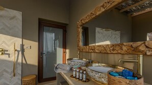 A bathroom with a double sink, a shower, and a large mirror with a wooden frame.