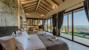 A bedroom with a large bed, a desk, and a view of the landscape.