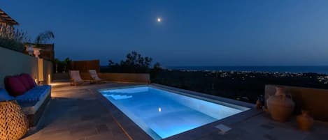A rooftop pool with a view of the city at dusk.