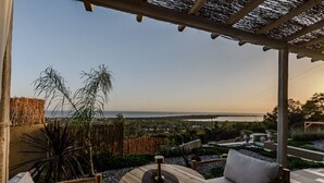 An outdoor seating area with a table and chairs, overlooking a coastal landscape.