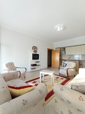 A living room with a sofa set, a coffee table, and a television on a wall.