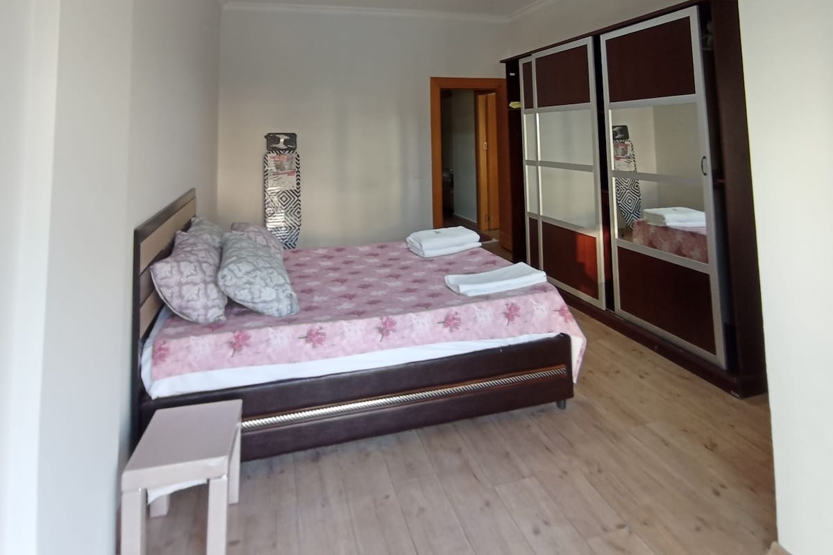 A bedroom with a bed, a bedside table, a wardrobe, and a ceiling light.
