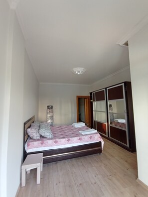 A bedroom with a bed, a bedside table, a wardrobe, and a ceiling light.