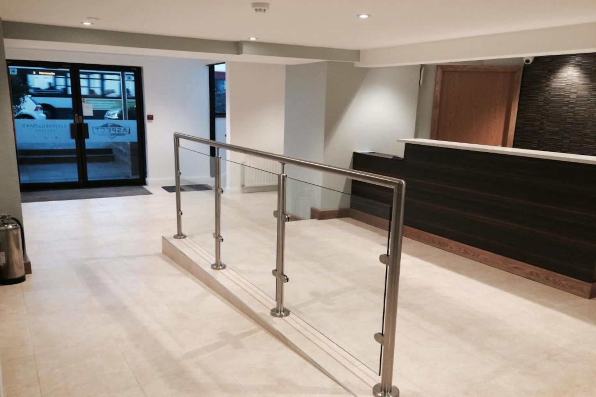 A reception area with a glass partition, a reception desk, and a metal barrier.