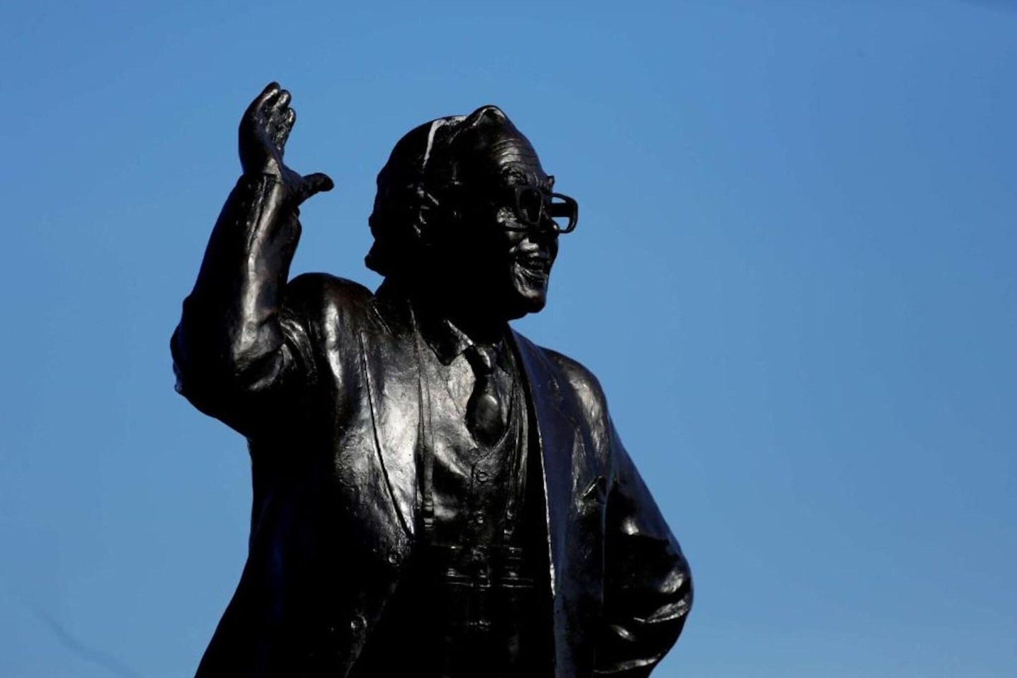Une statue représentant une figure en costume, le bras levé.