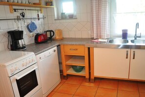 Eine kleine Küche mit einem weißen Backofen, einer Kaffeemaschine und einem Toaster auf der Arbeitsplatte.