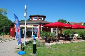Un restaurante con terraza, un toldo rojo y una bandera.