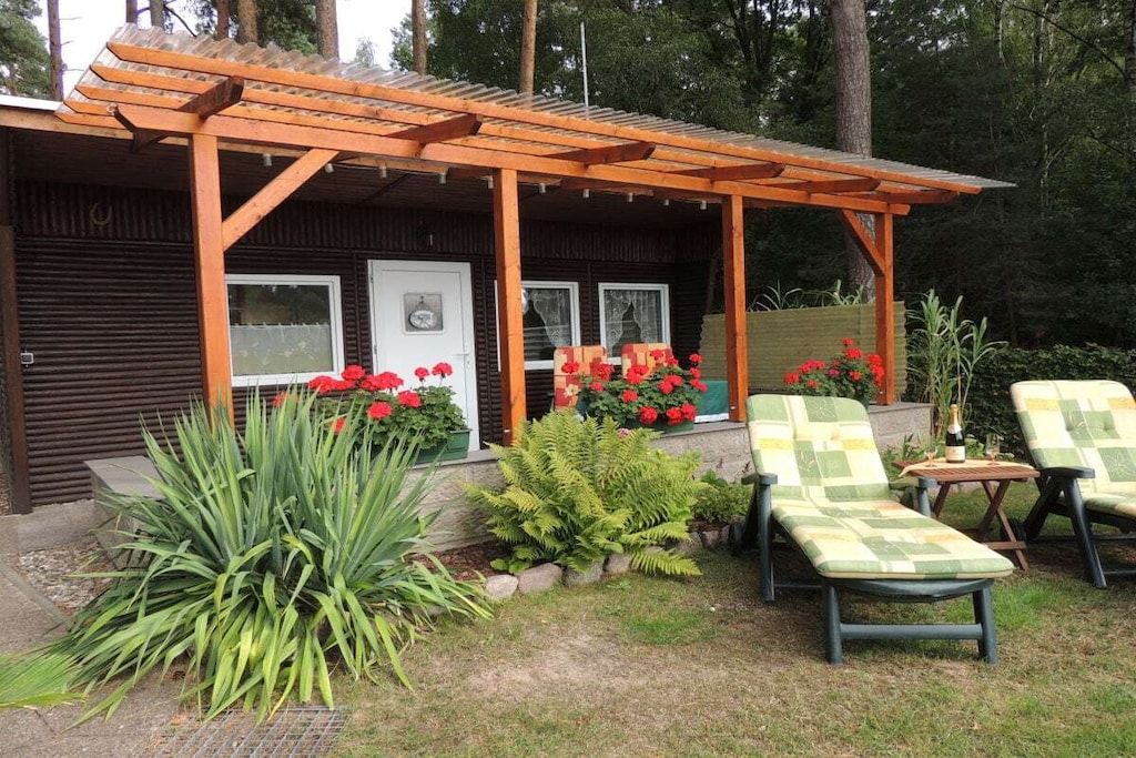 A wooden structure with a pergola, outdoor seating with cushions, and potted plants.