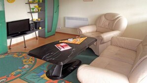 Un soggiorno con un divano, una TV su un mobile, un tavolino e un tappeto colorato.
