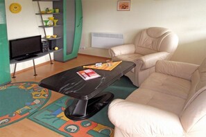 A living room with a sofa, a TV on a stand, a small table, and a colorful rug. - Holiday home Molchow (Molchow)