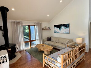 Una sala de estar acogedora con un sofá, una mesa de centro de madera, una chimenea y un ventanal con cortinas.