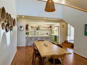 A spacious kitchen with a central island, wooden flooring, and a dining area with a table and chairs. - Birdies Beach House - Relaxing & Cosy Beach house on Kangaroo Island (Baudin Beach)