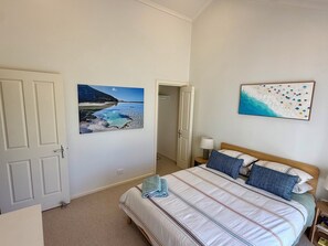 Ein Schlafzimmer mit einem Bett, einem Strandbild und einer Tür.