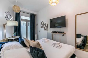 A hotel room with two beds, a television, a clock, and a mirror. - Cosy Studio - 2P - Parmentier / Voltaire (Paris)