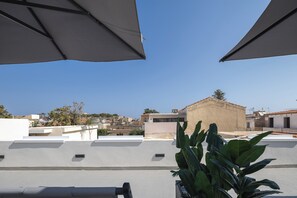 En tagterrasse med udendørs siddepladser og udsigt over bybilledet, samt en bygning med en kuppel.