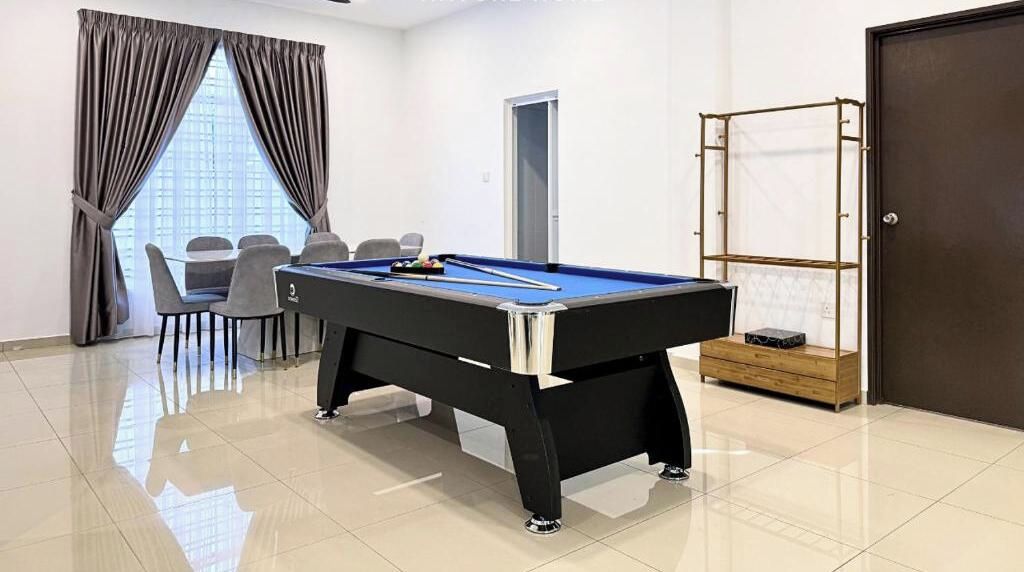 A pool table in a room with a door, a window with curtains, and a seating area with chairs.