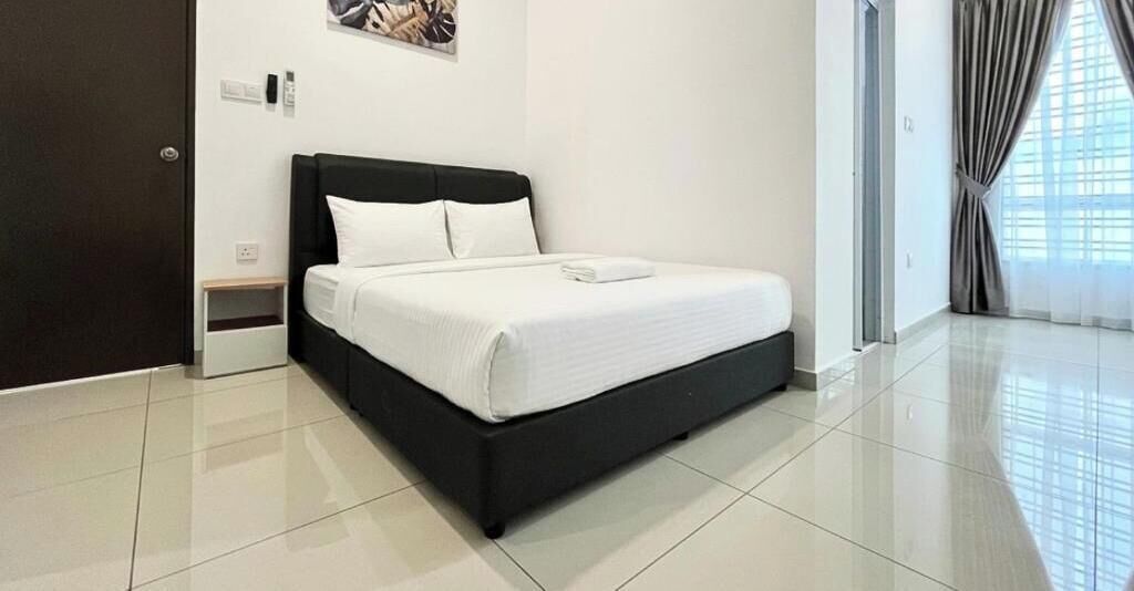 A modern bedroom with a black bed frame, white bedding, and a small bedside table.