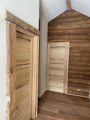 A hallway with wooden walls and flooring, leading to two doors. - A natural paradise just 20 minutes from Vars—a magnificent chalet in the heart of the Ubaye Valley (Saint-Paul-sur-Ubaye)