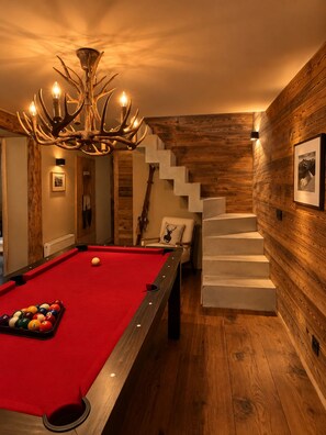 A pool table with a red felt surface, a chandelier with antler-like branches, and a staircase against a wooden wall. - A natural paradise just 20 minutes from Vars—a magnificent chalet in the heart of the Ubaye Valley (Saint-Paul-sur-Ubaye)