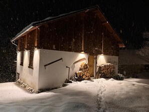 A wooden cabin with a snow-covered exterior, a stack of firewood, and a snow-covered ground. - A natural paradise just 20 minutes from Vars—a magnificent chalet in the heart of the Ubaye Valley (Saint-Paul-sur-Ubaye)