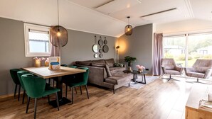 Una sala moderna con comedor, un sofá, dos sillones y una mesa con sillas.