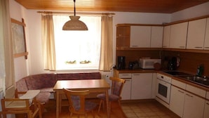 A compact kitchen with a dining area, including a table, chairs, and a built-in oven. - Farmhouse with 2 bedrooms (Elterlein OT Hermannsdorf)