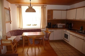 A compact kitchen with a dining area, including a table, chairs, and a built-in oven. - Farmhouse with 2 bedrooms (Elterlein OT Hermannsdorf)