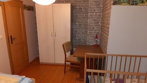 A room with a wooden floor, a bed with a patterned bedspread, a wooden wardrobe, a table with a chair, and a crib. - Farmhouse with 2 bedrooms (Elterlein OT Hermannsdorf)