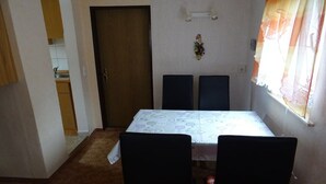 A dining area with a table and chairs, a door, and a window with curtains. - Holiday home with 2 bedrooms (Reinhardtsdorf)