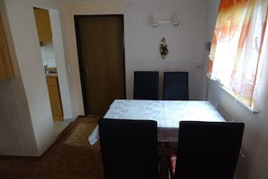 A dining area with a table and chairs, a door, and a window with curtains. - Holiday home with 2 bedrooms (Reinhardtsdorf)