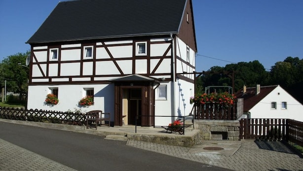 A traditional half-timbered house with a dark roof, a front entrance, and flower boxes on the windows. - Holiday home with 2 bedrooms (Reinhardtsdorf)