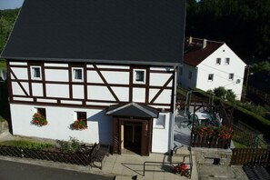 A traditional half-timbered building with a dark roof, a small entrance, and flower boxes on the ground floor. - Holiday home with 2 bedrooms (Reinhardtsdorf)