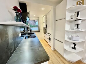 Een moderne keuken met een rvs aanrechtblad, ingebouwde apparatuur en witte keukenkastjes.