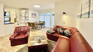 Ein Wohnzimmer mit einem roten Ledersofa, einem Holztisch und einem Essbereich mit Tisch und Stühlen.