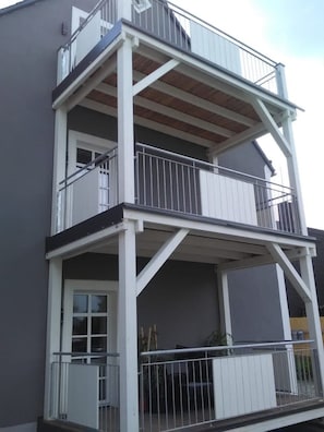 Un immeuble à plusieurs étages doté de balcons, de garde-corps et d’une fenêtre.