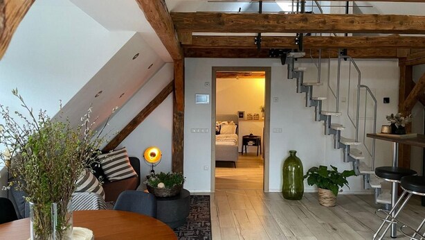 Ein modernes Interieur mit Holzboden, einer Treppe und einer Essecke mit Tisch und Stühlen.