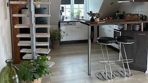 Eine moderne Küche mit Holzbalkendecke, einer Metall-Spirale und einer Bar mit Hockern.