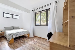 A bedroom with a bed, a desk, a chair, a window with curtains, and a door. - 10 minutes from the public beach at GND GAUBE: a charming house with a pool (Grand Gaube)