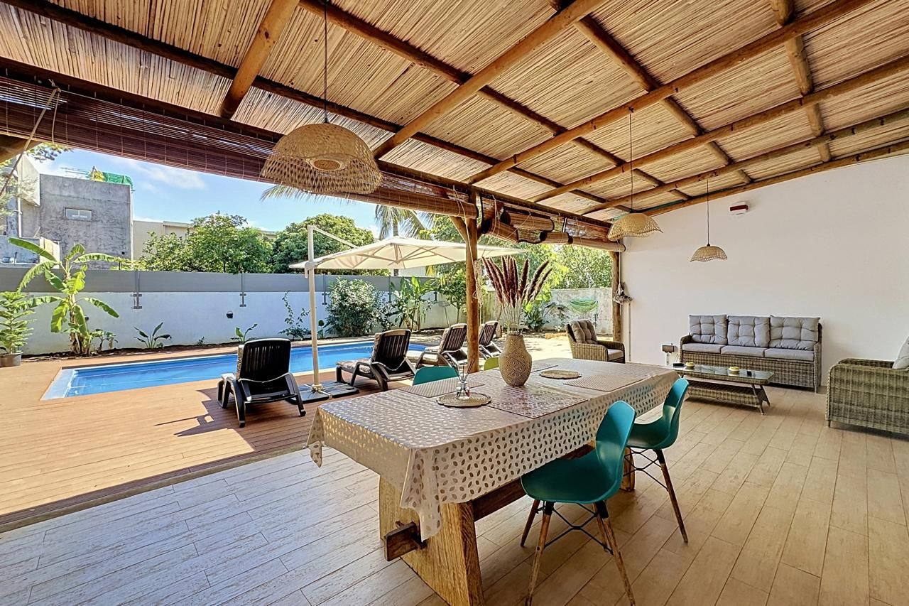 An outdoor patio with a pool, wooden deck, and a table with chairs.