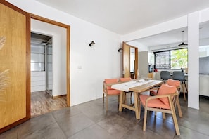 A modern dining area with a wooden table and chairs, a kitchen in the background, and a sliding door leading to a storage space. - 10 minutes from the public beach at GND GAUBE: a charming house with a pool (Grand Gaube)