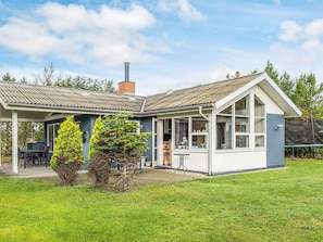 A two-story house with a covered patio, a chimney, and a well-maintained lawn. - 6 Person Holiday Home in Saeby (Sæby)