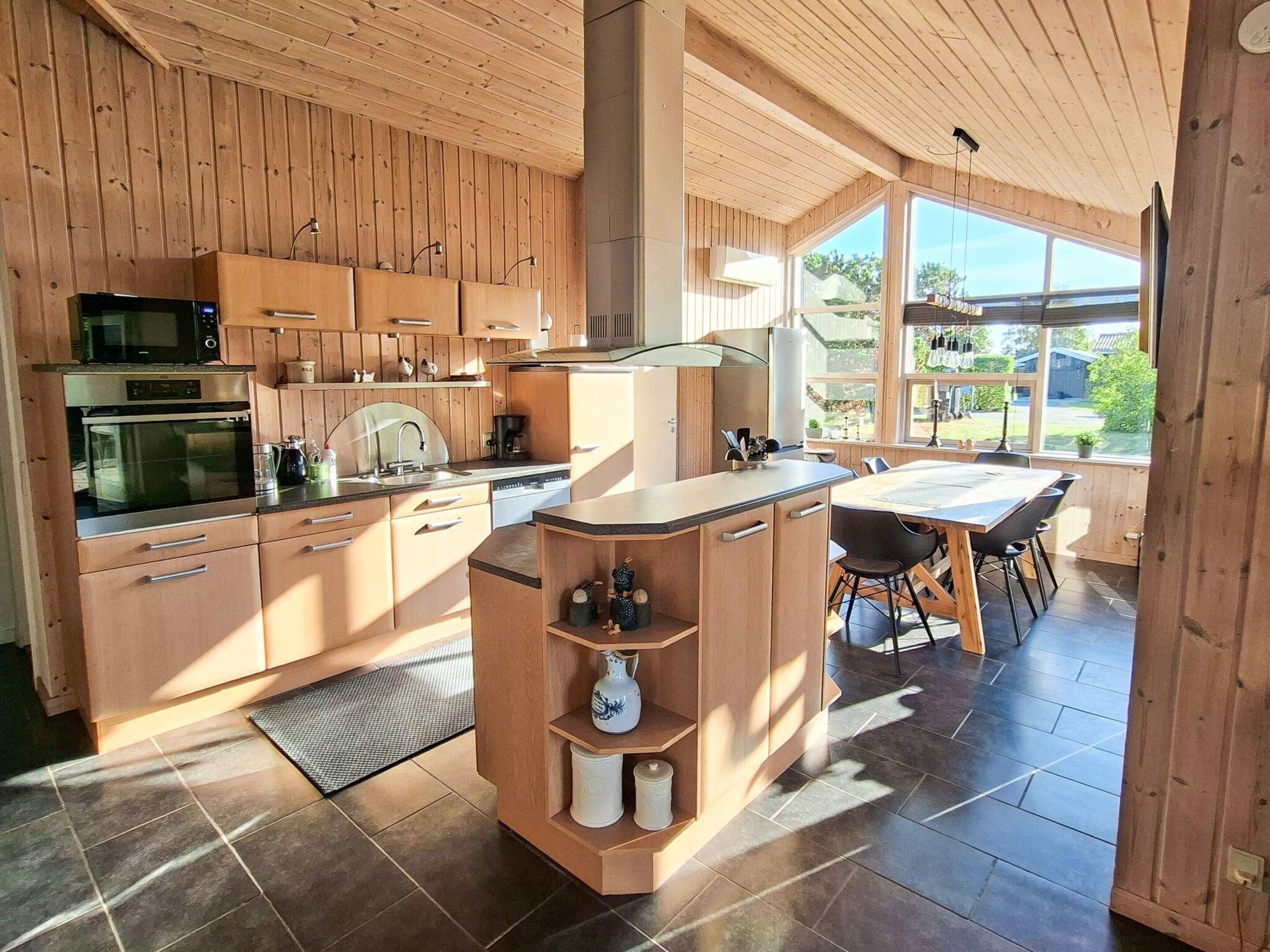 Cozinha moderna com armários de madeira, uma ilha central e área de refeições com vista.