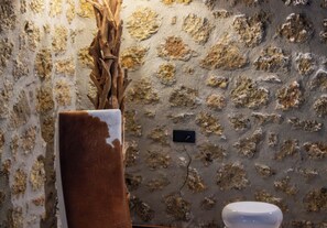 A stone wall with a power outlet and a vase with a brown object.