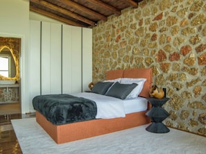 A bedroom with a stone wall, a bed with white bedding, and a wooden ceiling. - Heartbeat Villa One, Heartbeat Mountain Escapes (Xylokastro - Evrostina)