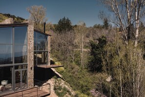 Un bâtiment moderne doté de grandes fenêtres et d’un balcon donnant sur une zone boisée.