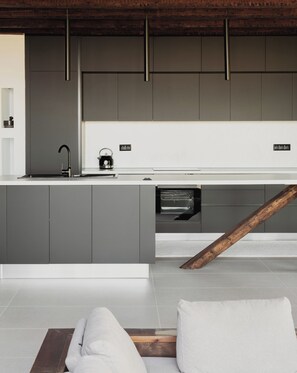 Une cuisine moderne avec des meubles de couleur grise, un lave-vaisselle encastré et une poutre en bois.